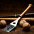 Baseball-inspired BBQ spatula with a stainless steel head and wooden baseball bat handle, surrounded by baseballs and bats